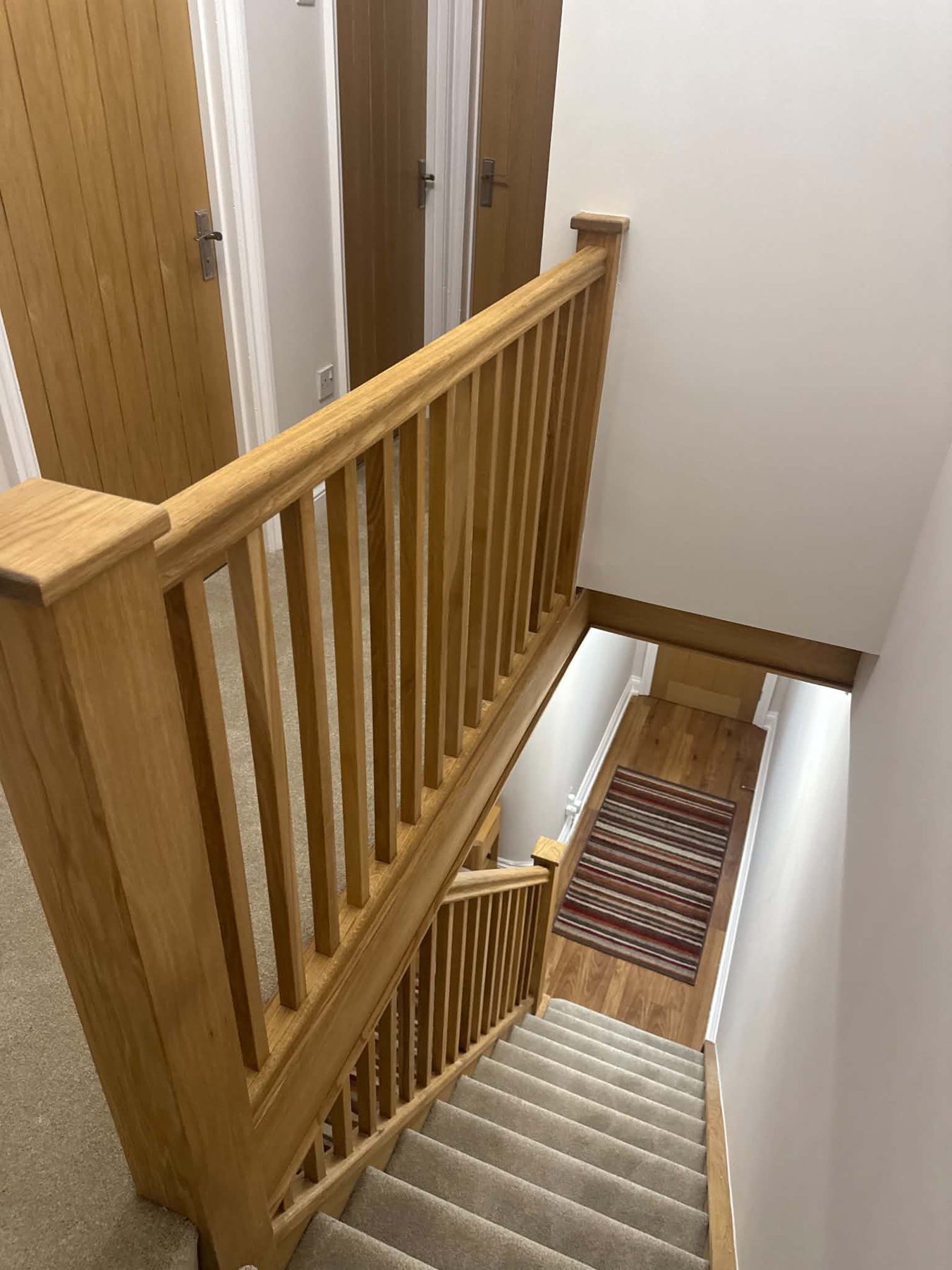 Glass balustrade with oak frame, tiled hallway